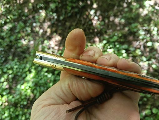Main dans la verdure tenant un couteau artisanal