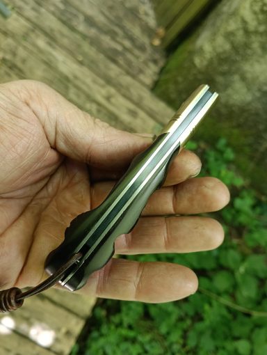 Un outil en métal tenu dans une main, avec une forme allongée et un cordon.