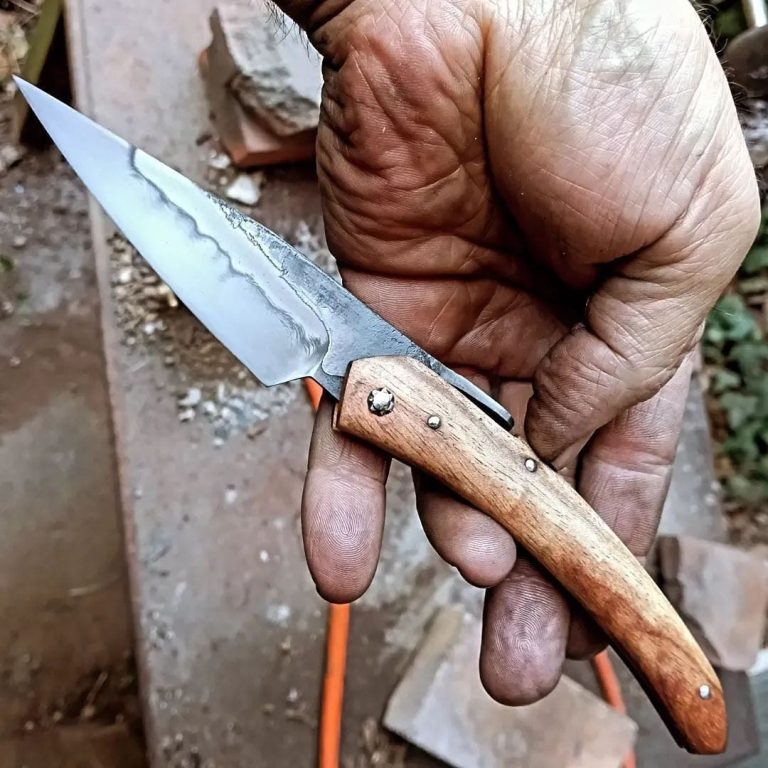 Couteau artisanal avec une lame en acier carbone et un manche en bois rouge.