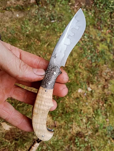 Couteau artisanal avec une lame courbée et un manche en bois élégant.