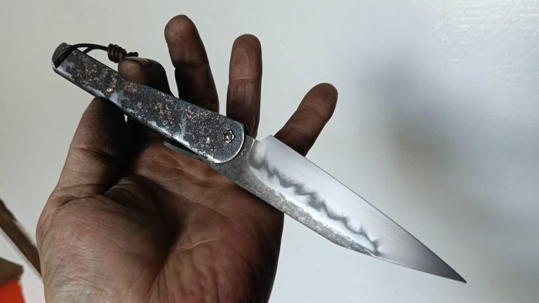 Couteau artisanal avec une lame en acier carbone et un manche en bois rouge.