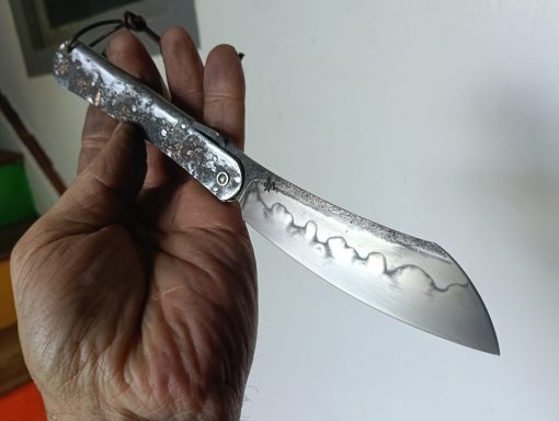 Couteau avec une lame stylisée, tenu par une main.